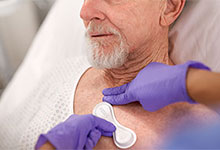 Ein Sensor wird auf der Brust eines &auml;lteren Patienten in einem Krankenhausbett platziert.