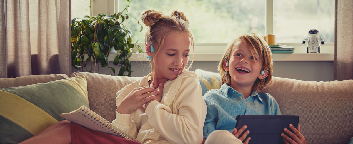 Kinder, die Philips Open-Ear-Kopfh&ouml;rer f&uuml;r Kinder verwenden, um ein Video anzusehen und sich freuen